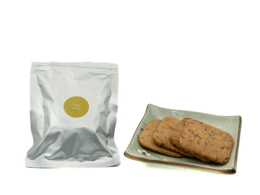 Coffee cookies Silver packaging with a gold label next to a plate of cookies on a white background