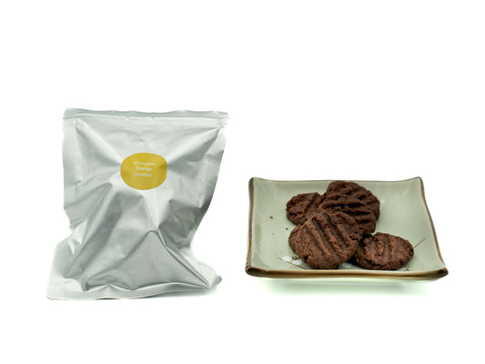White packaging with a yellow label next to a plate of choc orange cookies on a white background