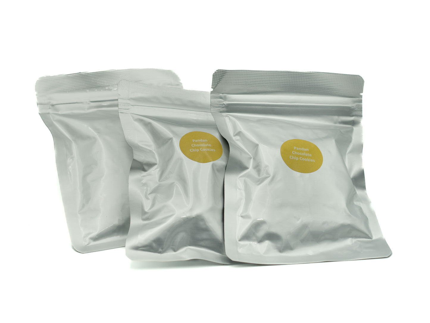 Three white snack bags with yellow labels on a white background, pandan choc chip cookies