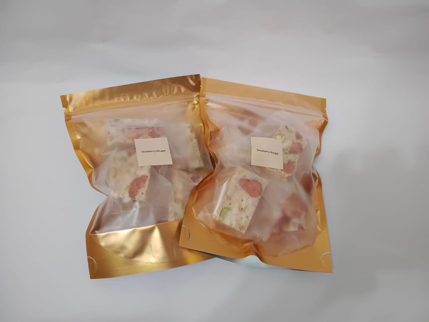 Two packages of food in gold packaging on a white background