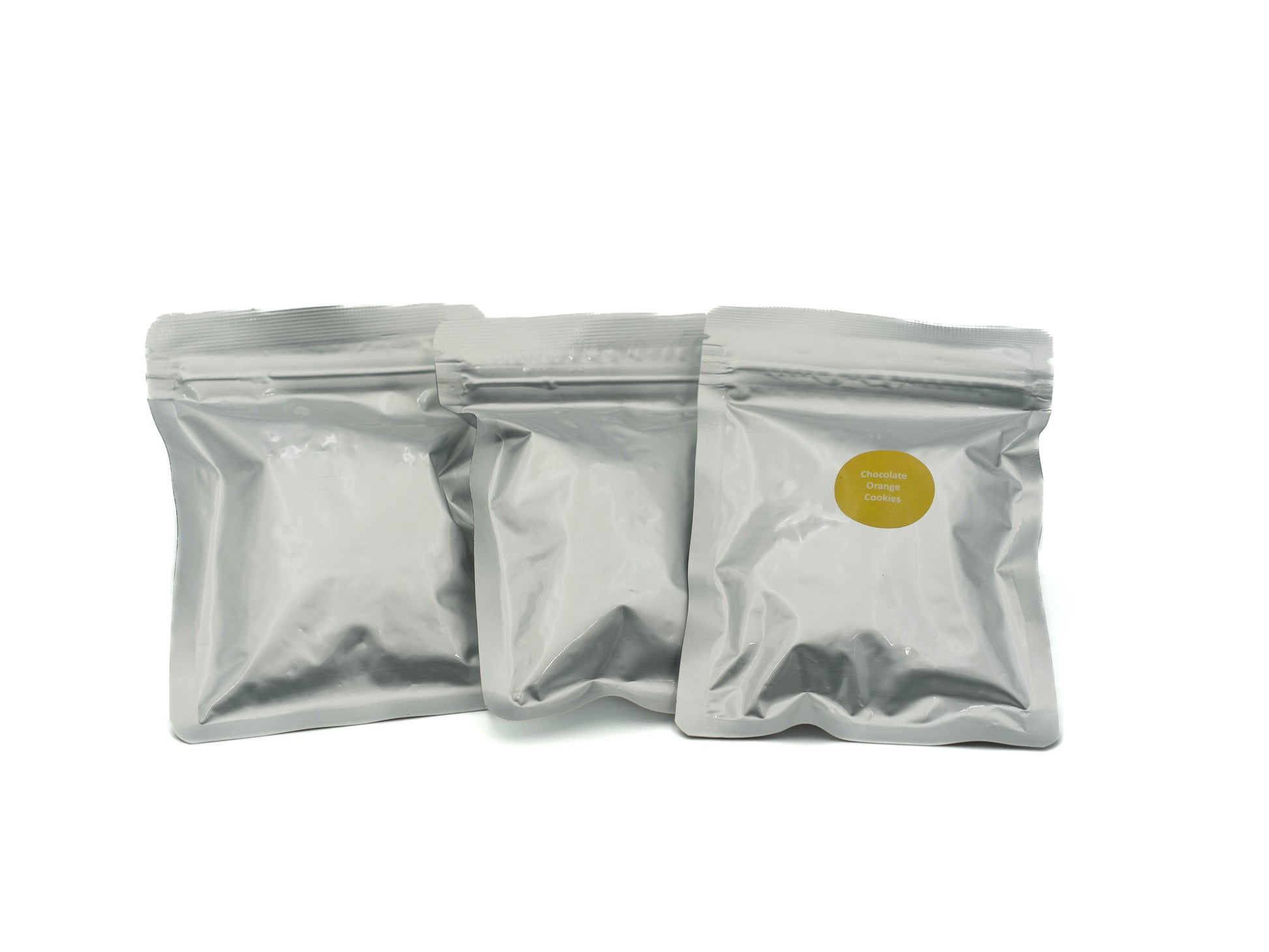 Three silver packaging pouches with a yellow label on a white background